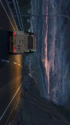 a car driving down a road next to the ocean at night with its lights on