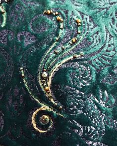 closeup of green and gold brocade with beads on the beaded end of it