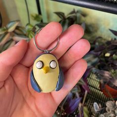 a hand holding a keychain with a yellow bird on it's face