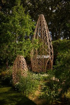 two large wooden sculptures in the middle of a garden with grass and trees around them