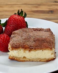 two strawberries sit on a plate next to a piece of cake