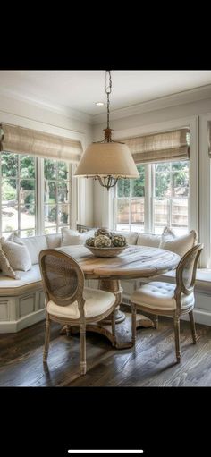 a dining room table with four chairs and a bench in front of the bay window