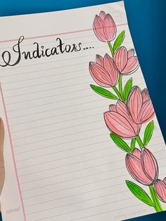 a hand holding up a piece of paper with pink flowers on it and the words indiators written in black ink