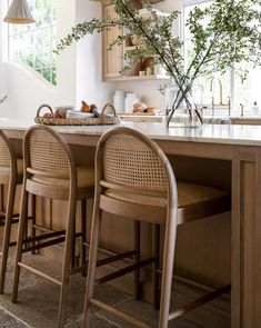 a kitchen with wooden cabinets and stools next to an island counter topped with plants