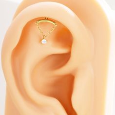 an ear with a single diamond in the middle and a gold chain around it's side