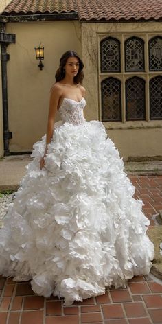 a woman in a white dress standing on a brick walkway