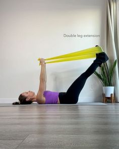 a woman is doing an exercise on the floor while holding a yellow object above her head