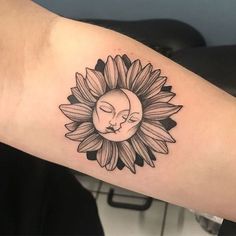 a woman's arm with a sunflower and a sleeping face tattoo on it