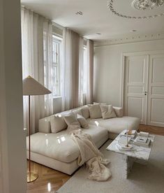 a living room with white furniture and curtains