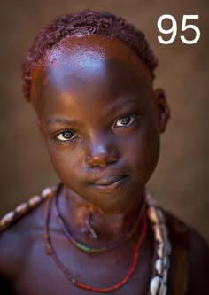 a close up of a child with brown skin and necklaces on her neck, looking at the camera