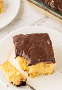 a piece of cake with chocolate frosting on a white plate next to a fork