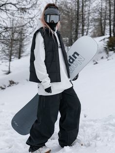 a person standing in the snow with a snowboard and goggles on their head