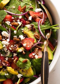 a salad with spinach, strawberries, avocado and feta cheese