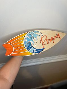 a person holding up a surfboard with the word roma on it