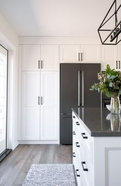 a black refrigerator freezer sitting inside of a kitchen next to white cabinets and drawers