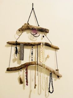 a wall hanging made out of driftwood with beads and necklaces attached to it