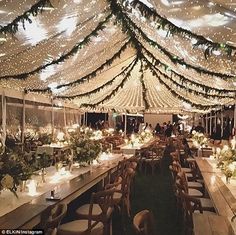 the inside of a tent decorated with lights and greenery