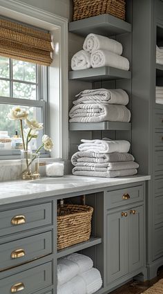 a bathroom with gray cabinets and lots of white towels on top of the countertop