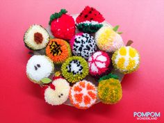 a bowl filled with lots of different types of pom poms on top of a pink surface