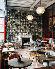 an empty restaurant with tables and chairs in front of a brick wall that has plants growing on it