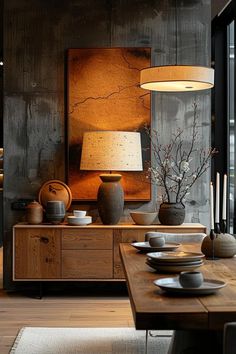 a table with plates and vases on it in front of a large wall mounted painting