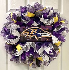 a purple and white wreath with the baltimore ravens logo on it hanging on a door