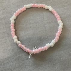 the pink and white beaded bracelet has a silver charm on it's end