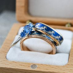 two gold rings with blue stones in a wooden box