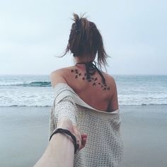 the back of a woman's neck with tattoos on her left shoulder and right arm