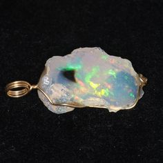 This pendant features a raw, uncut Ethiopian opal.  The stone weighs in at 13 carats and is set in solid 14k yellow gold. Ethiopian opal has quickly risen to prominence since the discovery of material in the Welo province in late 2007.  This mine proved to be truly extraordinary, producing a wide variety of high-quality opals, ranging from black to white and with every possible color and pattern of fire. This is a very striking stone.  It is has a clear base set off by a single spot of pure blac Collectible Opal Gemstone Jewelry, Collectible Opal Jewelry With Gemstones, Opal Necklace Silver, Opal Gifts, Schmuck Gold, Opal Birthstone, Rainbow Opal, Opal Pendant Necklace, Raw Opal