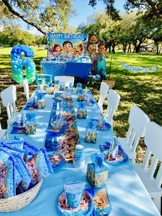 a table set up for a birthday party with blue and white plates, napkins and decorations