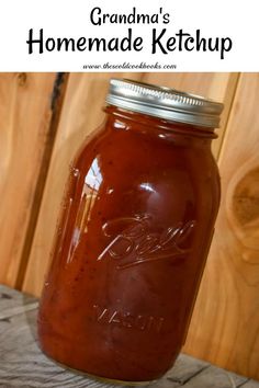 a jar filled with homemade ketchup sitting on top of a wooden table