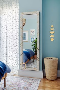 a large mirror sitting on top of a wooden floor next to a blue chair and potted plant