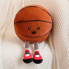 a stuffed toy basketball sitting on top of a white blanket with red shoes next to it