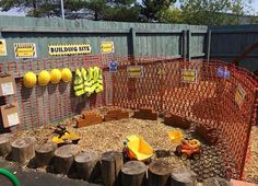 an outdoor play area with wooden logs and construction signs on the fenced in area