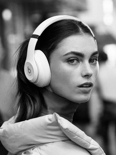 a woman with headphones on her ears is looking off to the side in black and white