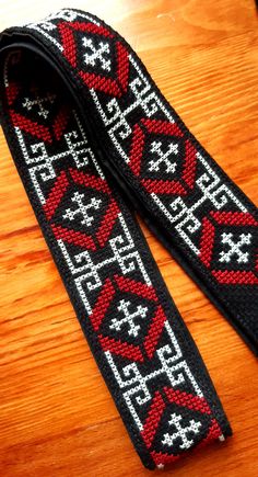 a pair of black and red knitted lanyards sitting on top of a wooden table