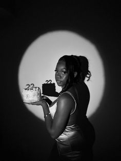 a black and white photo of a woman holding a cake