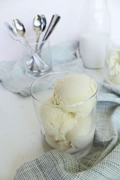 two glasses filled with ice cream sitting on top of a table next to spoons