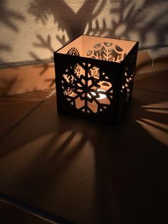 an intricate cut out candle holder on the floor with shadows cast by it's shadow