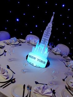 a table set up with plates and silverware for a new york cityscape centerpiece