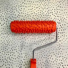 a red hair brush sitting on top of a white table next to a metal roller