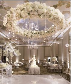 an elegant wedding reception with white flowers and chandelier hanging from the ceiling,