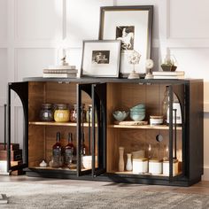 an open cabinet with bottles and pictures on the top shelf, next to a rug