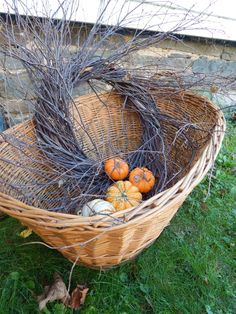 a basket filled with pumpkins sitting on top of a grass covered field next to a stone wall