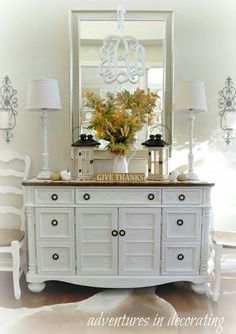 an image of a white dresser with flowers on top and two lamps next to it