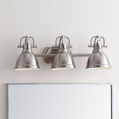 three light bathroom fixture with chrome finish and white glass shades on the wall next to a mirror