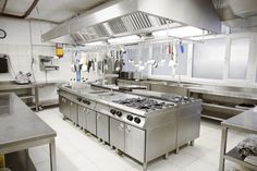 an industrial kitchen with stainless steel appliances and counter tops on the walls, along with hanging utensils