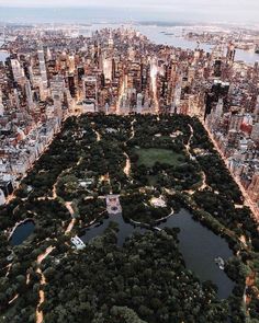 an aerial view of a city at night with lots of trees in the foreground