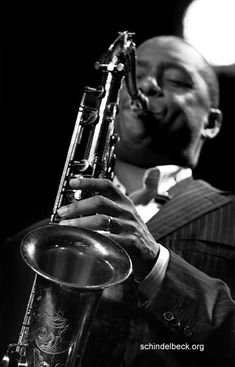 a man is playing the saxophone in black and white with his eyes closed while wearing a suit